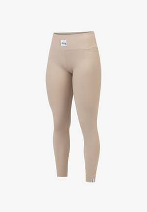 Beige ribbed leggings with a high waistband, featuring a small logo tag. The fabric appears stretchy and smooth, with a fitted silhouette.