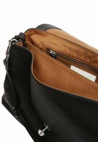 Borsa a mano in pelle nera con una superficie testurizzata, dotata di un interno color nocciola, tasca centrale con zip e minuteria in argento. Design con apertura superiore.