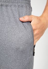 Grijze joggers gemaakt van textiel, met een elastische tailleband, een zijzak met rits en een grijze logo-accent op de dij.