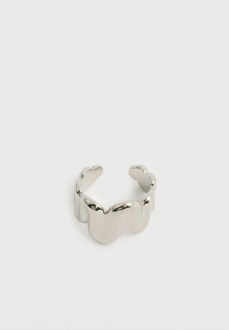 Ρυθμιζόμενο δαχτυλίδι σε ασημί απόχρωση με συνδεδεμένα σχήματα πεταλούδας, με λείες και αντανακλαστικές επιφάνειες σε λευκό φόντο.