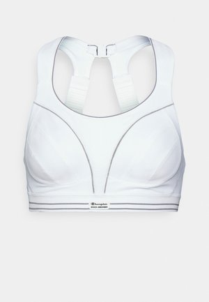 Soutien-gorge de sport blanc à dos nageur, avec un tissu texturé, des bonnets profilés, et une bande logo avec des rayures contrastées.