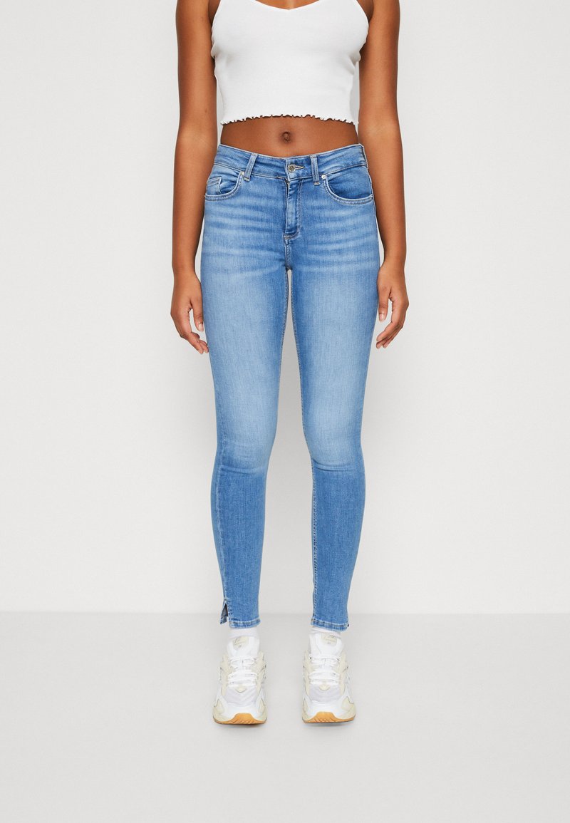 Ljust blå smala jeans med en klassisk femficksdesign, med en medelhög midja och sprund vid anklarna. Materialet verkar slätt och elastiskt.