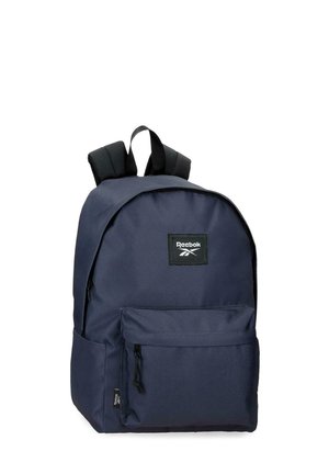 Mochila Reebok azul marino con un bolsillo delantero con cremallera, correas de hombro acolchadas negras y una asa superior para llevar, sobre fondo blanco.
