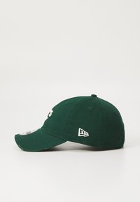 Grønn bomullslue med bøyd skjerm, med hvit brodert tekst og en logo på siden. Stoffet har en teksturert finish.