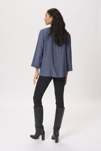 Maglietta blu scuro con pois testurizzati, vestibilità comoda, maniche larghe, abbinata a jeans skinny neri e stivali neri in pelle con tacco fino al ginocchio.