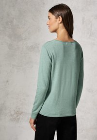 Mięta zielona, długi rękaw sweter z miękkiego dzianiny, z okrągłym dekoltem i luźnym krojem, zestawiony z czarnymi spodniami.
