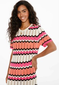 Pletené šaty s chevronovým vzorem v růžové, oranžové, černé a bílé barvě. Krátké rukávy, kulatý výstřih a volný střih. Texturovaná tkanina.