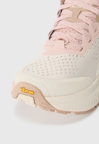 Lehká běžecká obuv s texturovaným krémovým a růžovým svrškem, šněrováním a logem Vibram® na podešvi pro lepší přilnavost.