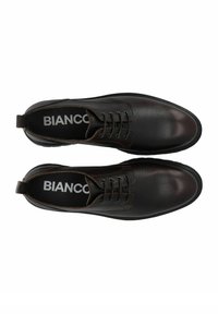 Zapatos de cuero negro con acabado texturizado, puntas redondas y siete ojales. Incluye una lengüeta en la parte trasera y suela de goma negra.