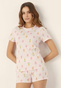 Pijamas de algodón en color rosa claro con un patrón repetido de conos de helado y polos en colores pastel. Diseño de mangas cortas y pantalones cortos.
