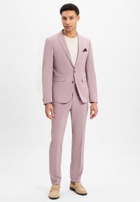 Hellrosa Anzug mit einreihigem Blazer und passender Hose. Strukturierten Stoff, Reverskragen und eine Brusttasche mit einem dunklen Akzent.