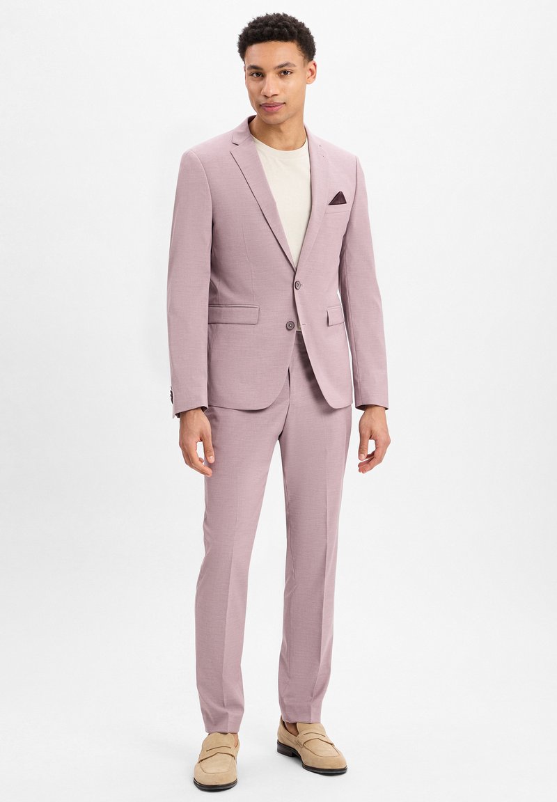 Hellrosa Anzug mit einreihigem Blazer und passender Hose. Strukturierten Stoff, Reverskragen und eine Brusttasche mit einem dunklen Akzent.