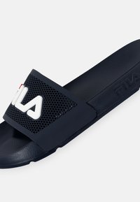 Navy blue slide sandal featuring a perforated strap with a white "FILA" logo, textured footbed, and a smooth sole for comfort.
