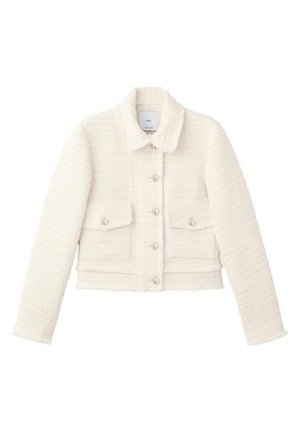 Veste blanche courte en tissu texturé avec col. Dotée de fermetures à boutons et de deux poches avant. Les bords sont légèrement effilochés.