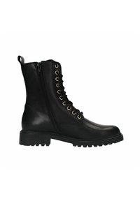Des bottes noires en cuir arrivent à la cheville, avec une fermeture éclair sur le côté, des œillets dorés pour les lacets, et une semelle robuste avec des crans prononcés.