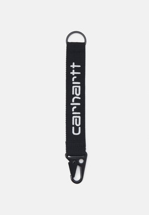 Porte-clés en tissu tissé noir avec une boucle et un clip en métal noir, présentant le logo "carhartt" en broderie blanche.