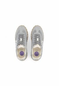 Baskets en daim gris avec un logo blanc, lacets plats et semelles en caoutchouc beige. L'intérieur présente une semelle intérieure avec un logo rond violet.