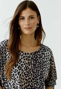 Bluse mit Leopardenmuster, lockerer Passform, rundem Ausschnitt und weichem Stoff. Verfügbar in einer Mischung aus Beigetönen und Dunkelbraun.