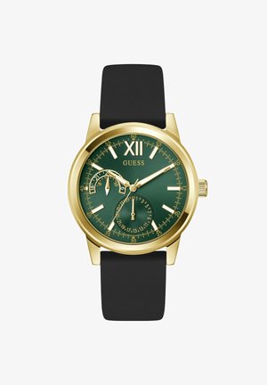 Ura Guess v zlato barvi z zelenim številčnico, črnim pasom, rimskim številom XII, podštevilčnicama za datum in 24-urne kazalce ter zlatimi oznakami ur in kazalci.
