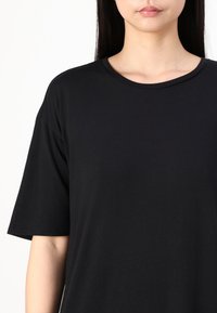 Mustapintainen t-paita, jossa on pyöreä pääntie ja lyhyet hihat, valmistettu sileästä puuvillamateriaalista. Yksinkertainen muotoilu ilman näkyviä kuvioita tai korostuksia.