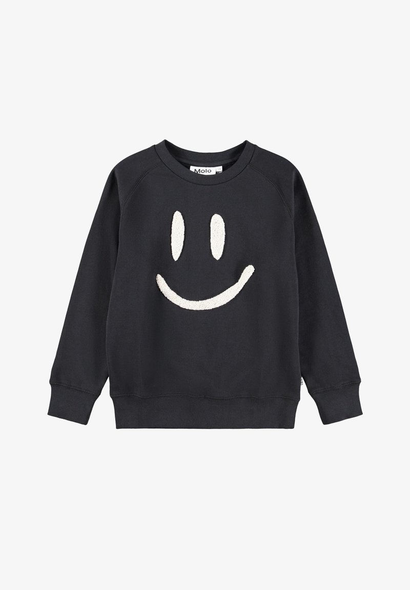 Sweat-shirt noir à manches longues avec un visage souriant blanc texturé sur le devant et un col rond, présenté sur fond blanc.