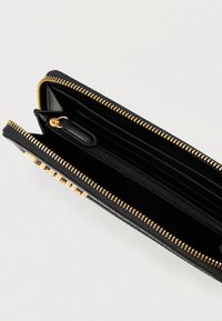 Μαύρο δερμάτινο πορτοφόλι με φερμουάρ, ανοιχτό για να δείξει το χρυσό φερμουάρ, πολλαπλές θήκες για κάρτες και κεντρική θήκη για νομίσματα με φερμουάρ.