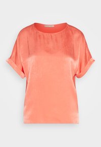 T-shirt en satin corail avec un col rond, des manches courtes roulées et une coupe loose. Texture lisse avec un léger éclat, idéal pour un look décontracté.