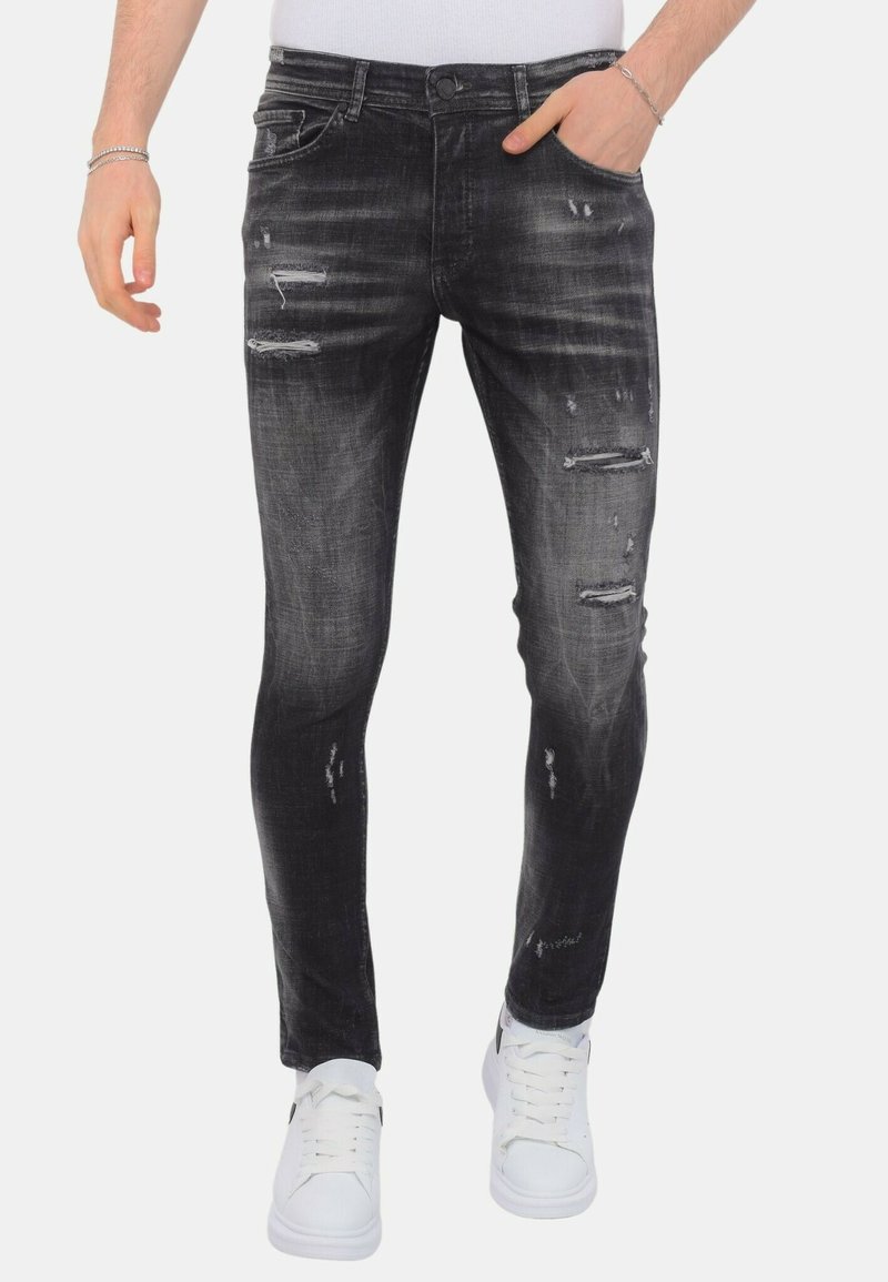 Zwarte denim skinny jeans met verwassen details, lichte vervaging en een vijf-pocket ontwerp, gecombineerd met witte sneakers.