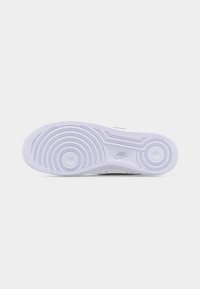 Semelle de chaussure de sport Nike blanche avec des motifs circulaires et le logo Nike embossé près du centre, présentée sur un fond clair uni.
