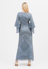 Zdobiona niebieska suknia długa z rozszerzanymi rękawami, przedstawiająca skomplikowane wzory i dopasowaną sylwetkę, podkreślona przez przezroczysty nakład.}}}]}**