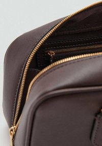 Geantă de piele maro, cu fermoar auriu, textură netedă și un buzunar mic interior cu închidere cu fermoar.