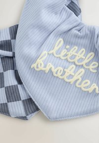 Coperta in cotone blu con una texture a righe. Accentata con il testo "fratellino" in crema e un design a strisce blu navy su un lato.