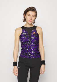 Lila Pailletten-Tanktop mit einem schwarzen Netzpaneel und tiefem V-Ausschnitt. Schwarze Sporthose mit weißer Markenbezeichnung. Schwarze Handgelenkbänder.