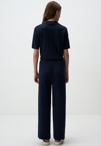 Navy geribbelde gebreide twee-delige set bestaat uit een collargemodel top met korte mouwen en wijde broekspijpen, met een elastische tailleband voor extra comfort.