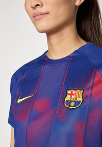 Nike Barcelona-tröja i blått med röda vertikala ränder; har en texturerad tygkvalitet och en vävd klubbemblem på bröstet.