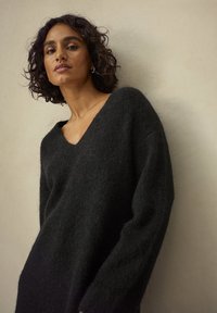 Sort, oversized sweater med V-hals, lavet af blødt, struktureret stof, med lange ærmer og en afslappet pasform.