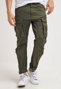 Olivově zelené cargo kalhoty s několika kapsami, slim fit a manžetovými lemy. Vyrobené z hladké bavlněné směsi, s uzávěrem na zip a knoflíky.