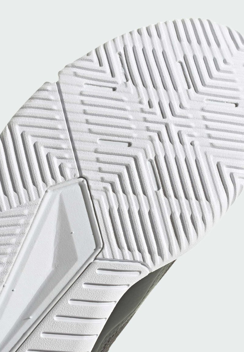 Gros plan d'une semelle de chaussure blanche avec des motifs en zigzag et des lignes texturées pour une meilleure adhérence.
