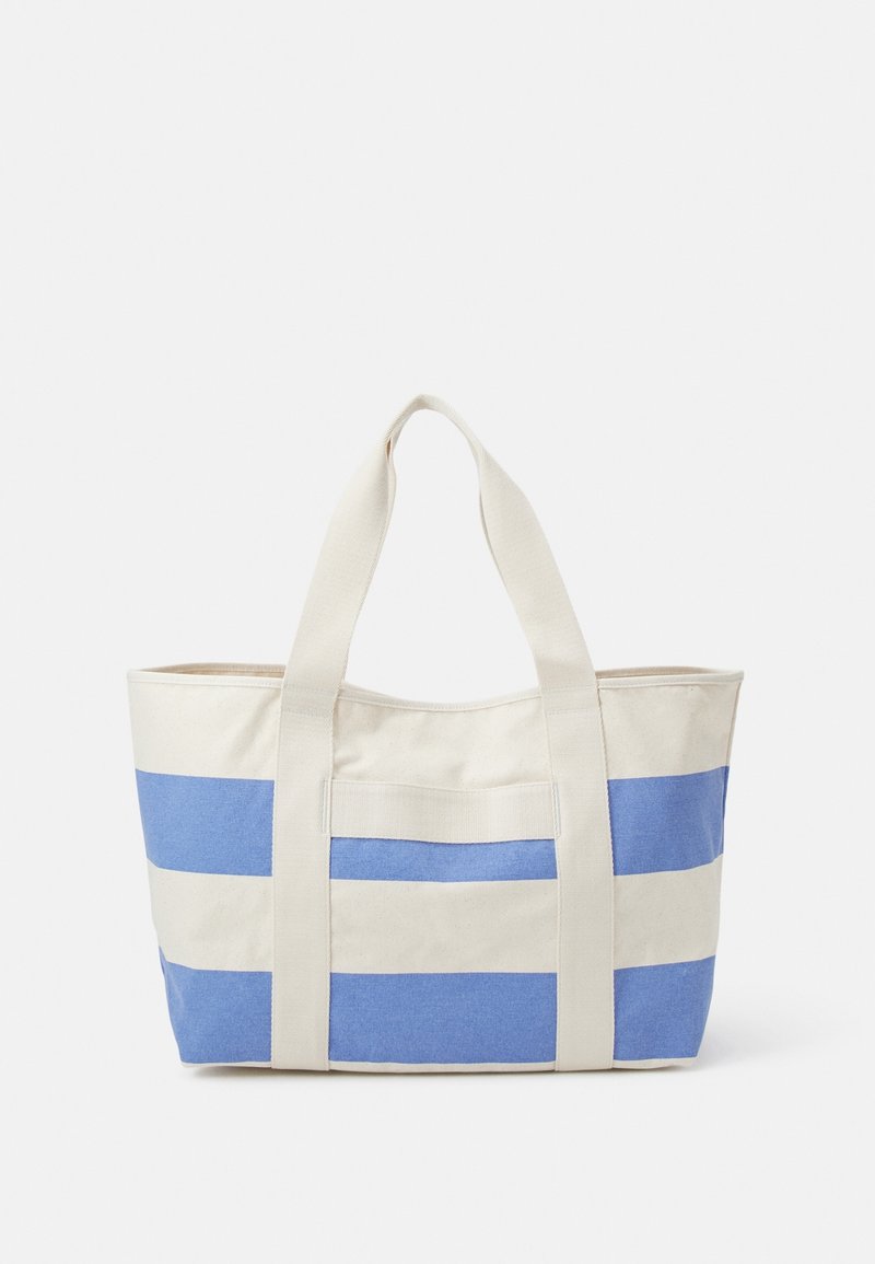 Sac cabas en toile avec de larges anses crème et des rayures horizontales bleues et crème sur le corps, présenté sur un fond uni.