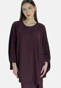 Weinrote Tunika mit rundem Ausschnitt, lockeren Ärmeln und einem fließenden, drapierten Design aus glattem Stoff.