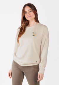 Felpa beige a maniche lunghe con scollatura rotonda, caratterizzata da un piccolo motivo ricamato floreale sul petto e un sottile accento del logo all'orlo.