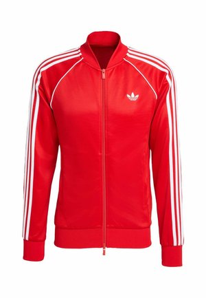 Casaco vermelho com fecho de correr, feito de tecido liso, com riscas brancas ao longo das mangas e um pequeno logótipo branco no peito.