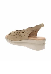 Sandalo in pelle beige perforata con design scallop, cinturino regolabile e suola a zeppa leggera. Suola piatta e testurizzata per una buona aderenza.