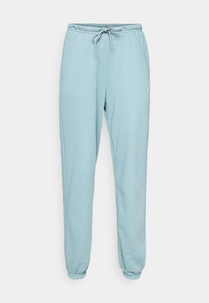 Lyseblå joggebukser laget av mykt stoff, med elastisk midjebånd med snor, to sidelommer og elastiske mansjetter ved anklene.