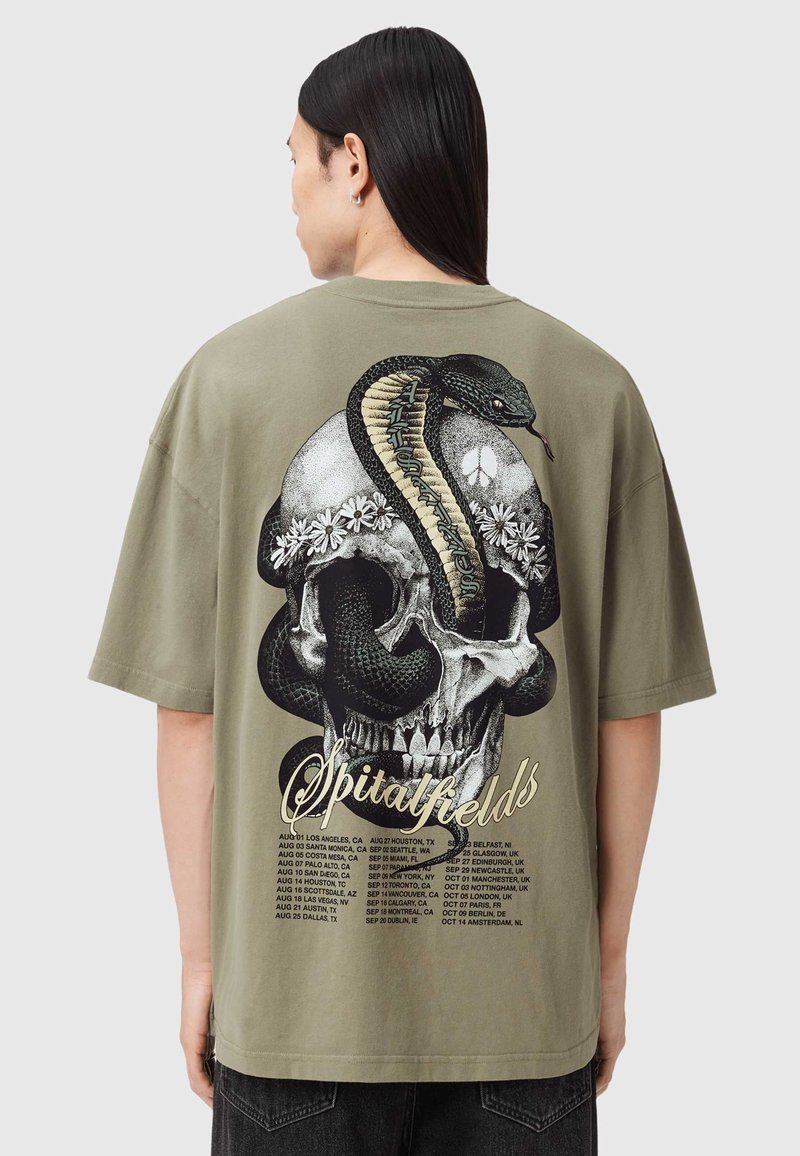 Olivengrøn oversized T-shirt med et motiv af en kranium med en slange, blomster og turnédatoer i kontrasterende farver. Korte ærmer, rund hals.