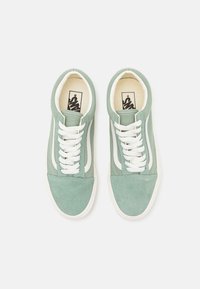 Sneakers verde in suede con lacci bianchi e accenti laterali, punta rotonda e foderatura in tessuto. Presenta un logo sulla linguetta.