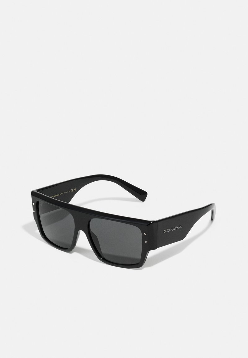 Ochelari de soare supradimensionați, negri, cu rame din plastic gros, lentile întunecate, cu cuie argintii la colțuri și logo-ul mărcii gravat pe lateral.