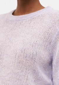 Lila stickad tröja med en lös, strukturerad textil och rundad halsringning. Designen har ett delikat, genomskinligt utseende.