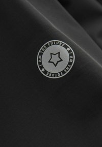 Tela negra con un logo circular que presenta una estrella, inscrito con "SOY EL FUTURO" en texto plateado contrastante. Textura suave.
