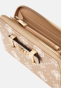 Beige Geldbörse mit Reißverschluss, weißem Blumenmuster, goldfarbener Hardware und internen Kartenfächern, die einen offenen Münzfach-Reißverschluss zeigt.